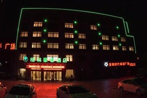 A building with multiple windows and a sign indicating a hotel. There are cars parked in front.