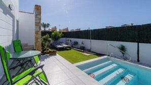 Ein Garten mit Swimmingpool, einem Steinsäule und einem grünen Rasen.