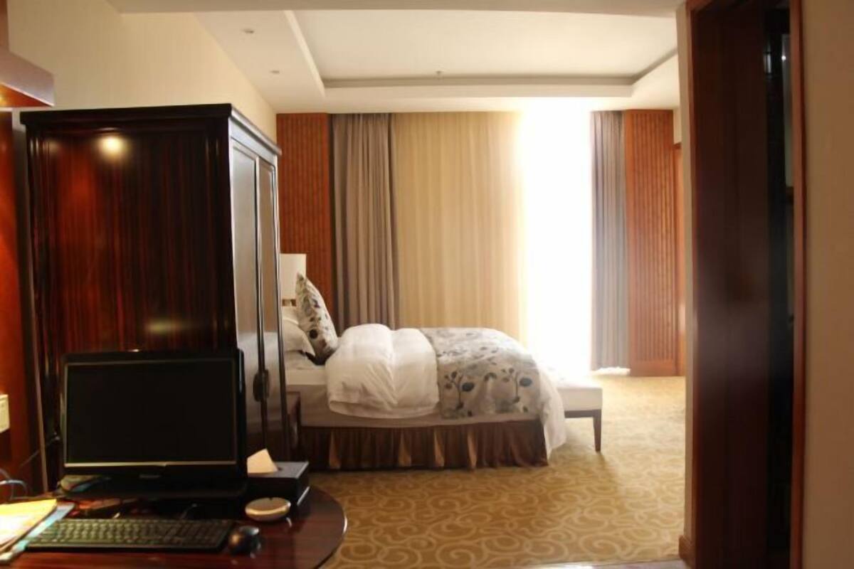 A hotel room with a bed, a desk with a computer, and a wardrobe.