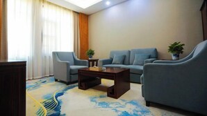 Una sala de estar moderna con un sofá, dos sillones, una mesita de centro y una planta en maceta.