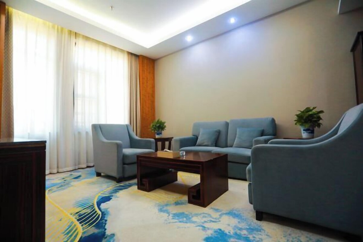 Una sala de estar moderna con un sofá, dos sillones, una mesita de centro y una planta en maceta.