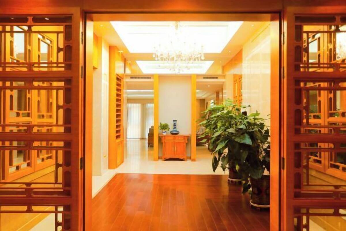 A hallway with wooden lattice doors, a chandelier, and a potted plant.
