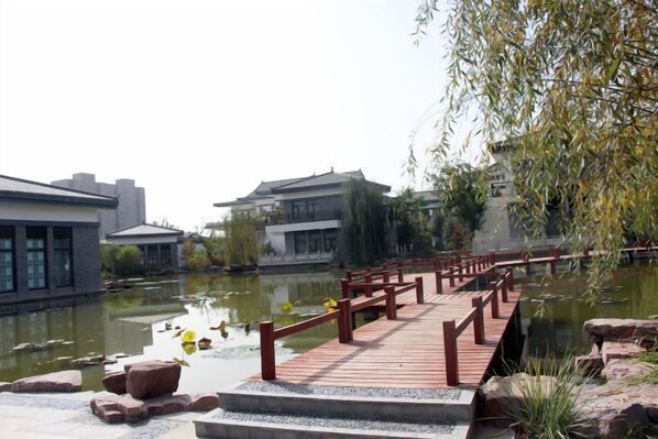 A wooden bridge over a pond with buildings on either side.