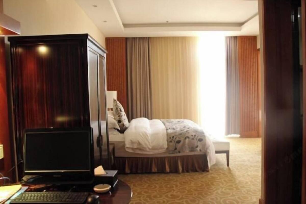 A hotel room with a bed, a desk with a computer, and a wardrobe.