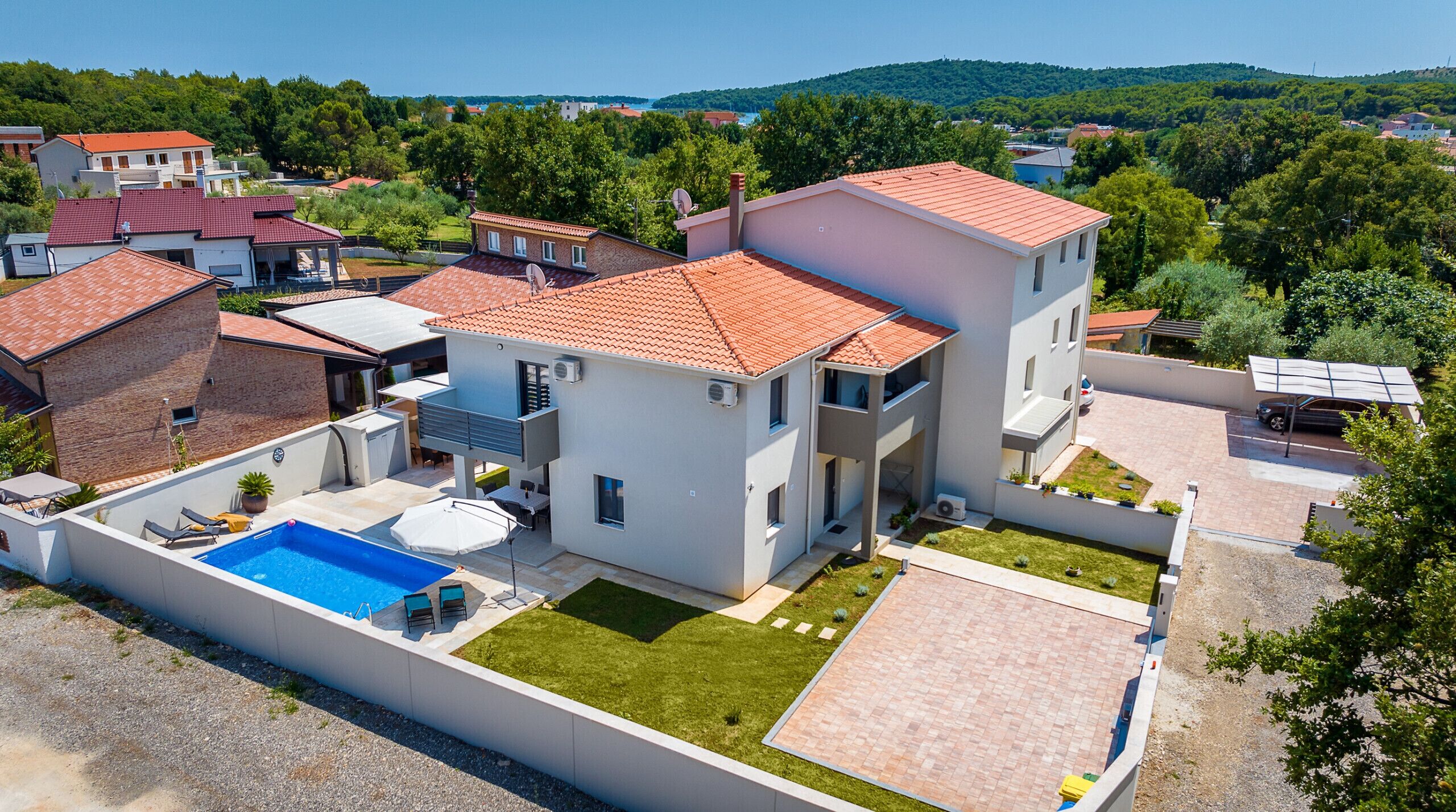 Ein modernes, zweistöckiges Haus mit Swimmingpool, überdachter Terrasse und Blick auf die umliegende Nachbarschaft.