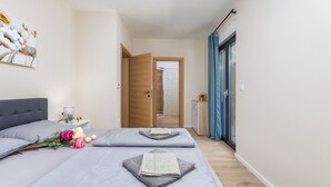 Una habitación de hotel moderna con una cama, una mesita de noche, un espejo y una puerta que da a un baño.