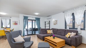 Una sala de estar moderna con un sofá gris, sillones y una mesa de centro de madera.