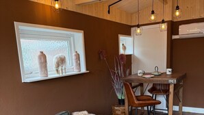 A cozy living room with a grey sofa, a wooden dining table, and a whiteboard on the wall.