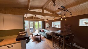 A spacious kitchen with wooden beams, a dining area with a bar, and a cozy seating area with a sofa and cushions.