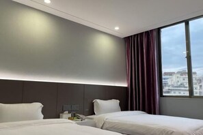 Une chambre d’hôtel avec deux lits, une table de chevet avec un téléphone et une fenêtre avec des rideaux.