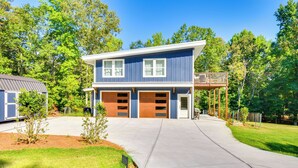 A two-story house with a garage, surrounded by trees and a well-maintained lawn. - Dock Access & Patio! Waterfront Apt in Hartwell (Hartwell)