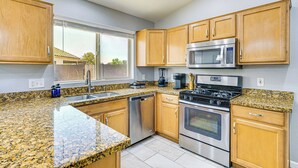 A kitchen with granite countertops, stainless steel appliances, wooden cabinets, and a window providing natural light. - Tucson Home w/ Patio, Grill & Mountain Views! (Tucson)