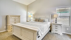A bedroom with a large bed, a nightstand, a dresser, and a window with a view of a brick wall. - Tucson Home w/ Patio, Grill & Mountain Views! (Tucson)