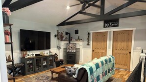 A living room with a fireplace, a television, and a large wooden door. - Idyllic Idaho Getaway: Your Spirit Lake Sanctuary (Spirit Lake)