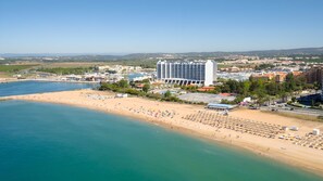 A coastal resort with a beachfront, a large hotel, and a marina.