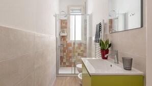 Une salle de bain moderne avec une douche à parois de verre, un lavabo blanc et un meuble vert.