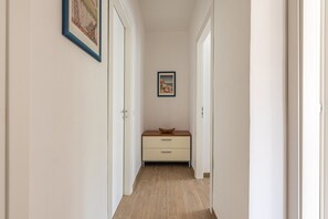 A narrow hallway with a wooden floor, a small cabinet with drawers, and two framed pictures on the walls. - La Casa Donna Vita a Mondello by Wonderful Italy (Palermo)