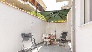 Un petit espace extérieur aménagé avec une table, des chaises et un parasol.