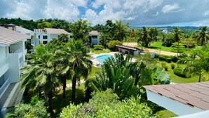 A resort with multiple white buildings, a swimming pool, and lush greenery including palm trees. - Cozy 3 Bedroom Penthouse in Playa Bonita (Las Terrenas)