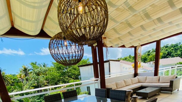 A spacious outdoor dining area with a glass-top table and wicker chairs, overlooking lush greenery and a clear sky. - Cozy 3 Bedroom Penthouse in Playa Bonita (Las Terrenas)