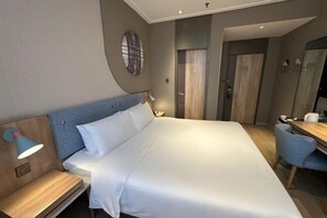 Ein modernes Hotelzimmer mit einem großen Bett, Nachttischen, einem Schreibtisch und einer Duschkabine.