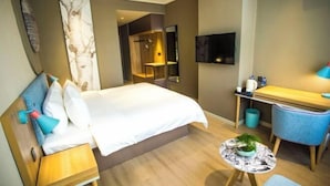 A modern hotel room with a bed, a desk, a chair, a small table with a plant, and a TV mounted on the wall. - Homeinn · neo (Shijiazhuang Xinbai Square Wanli Temple Pedestrian Street) (Shijiazhuang)