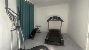 A small room with a treadmill, a stationary bike, and a bench. - Boffin Holiday Inn (Lijiang)