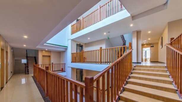 A multi-level interior with wooden railings, a staircase, and a skylight. - Boffin Holiday Inn (Lijiang)