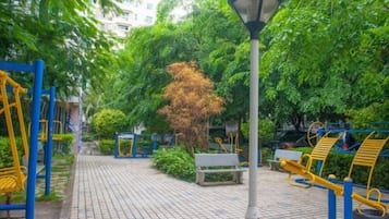 A park with exercise equipment, a lamp post, and a paved walkway.