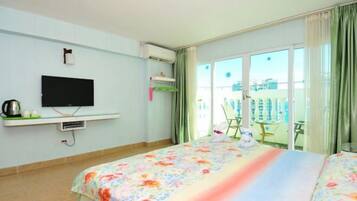 Habitación de hotel con cama, televisor, aire acondicionado y balcón con mesa y sillas.