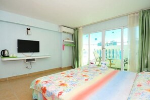 Ein Hotelzimmer mit Bett, Fernseher, Klimaanlage und einem Balkon mit Tisch und Stühlen.