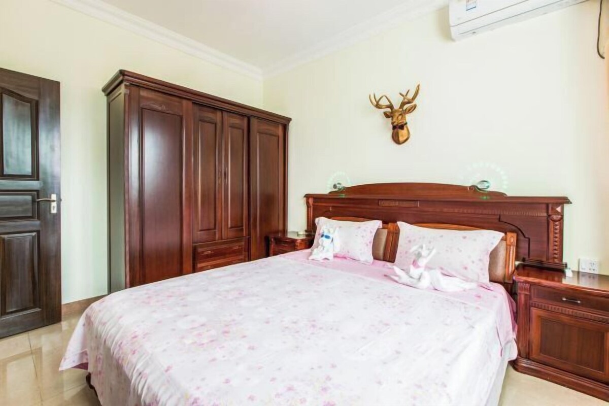 Ein Schlafzimmer mit einem großen Bett, einem Holzschrank und einem aufgehängten Hirschgeweih an der Wand.