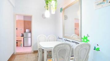 Un comedor con una mesa y sillas blancas, un espejo grande y una pared con una cita.