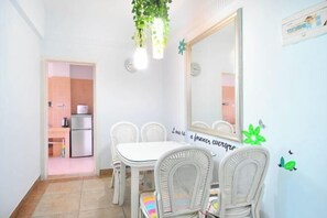 Ein Essbereich mit einem weißen Tisch und Stühlen, einem großen Spiegel und einer Wand mit einem Zitat.