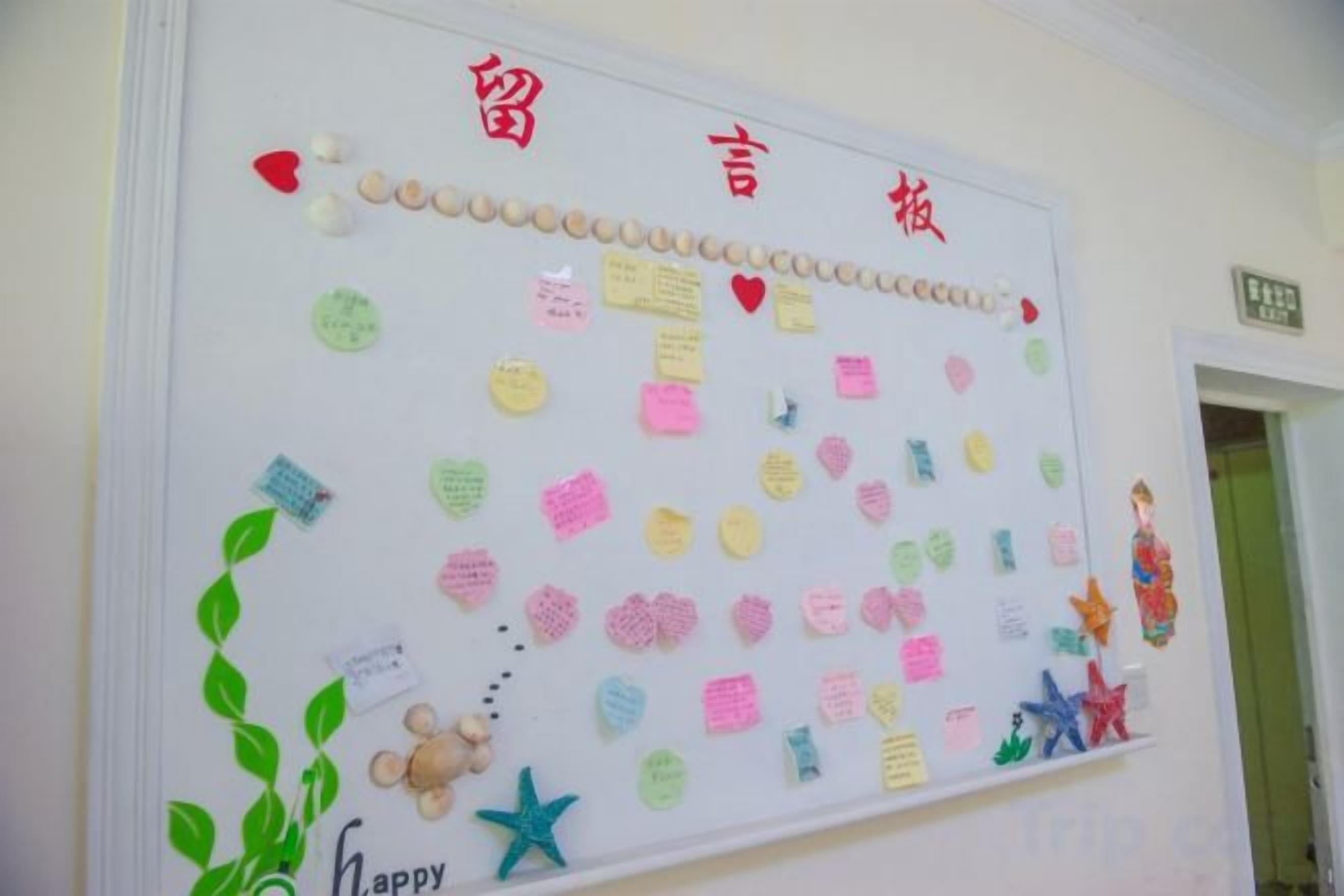A bulletin board with various notes and decorations, including a heart-shaped cutout and a small figurine.