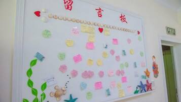 A bulletin board with various notes and decorations, including a heart-shaped cutout and a small figurine.