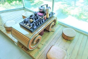 Een kamer met een houten vloer, een tafel met verschillende keukengerei en een groot raam met uitzicht op groen.