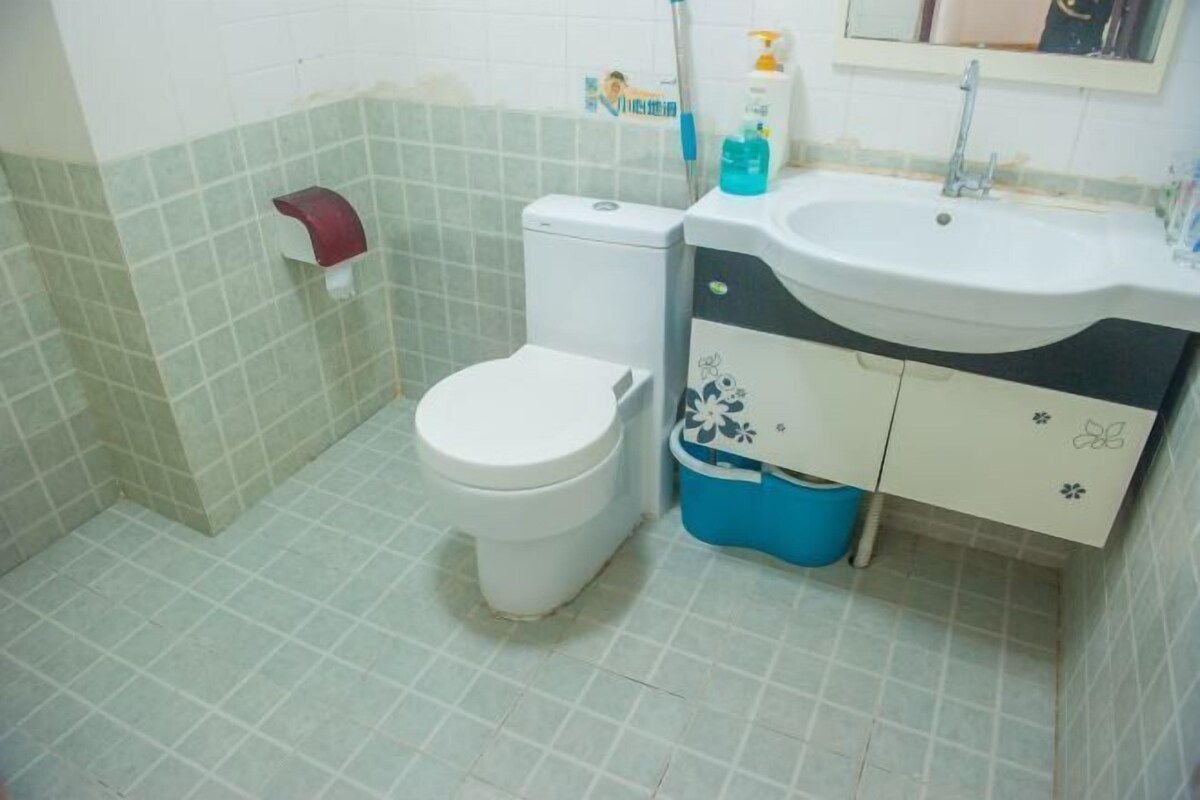 Ein kleines Badezimmer mit Toilette, Waschbecken und einer blauen Mülleimer.