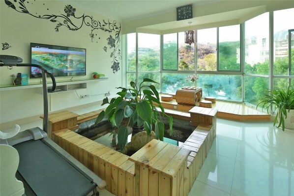 A modern room with a wooden sauna, a treadmill, a television, and large windows offering a view of greenery. - Haibian Dujiawu Hotel (Sanya Dadonghai) (Sanya)