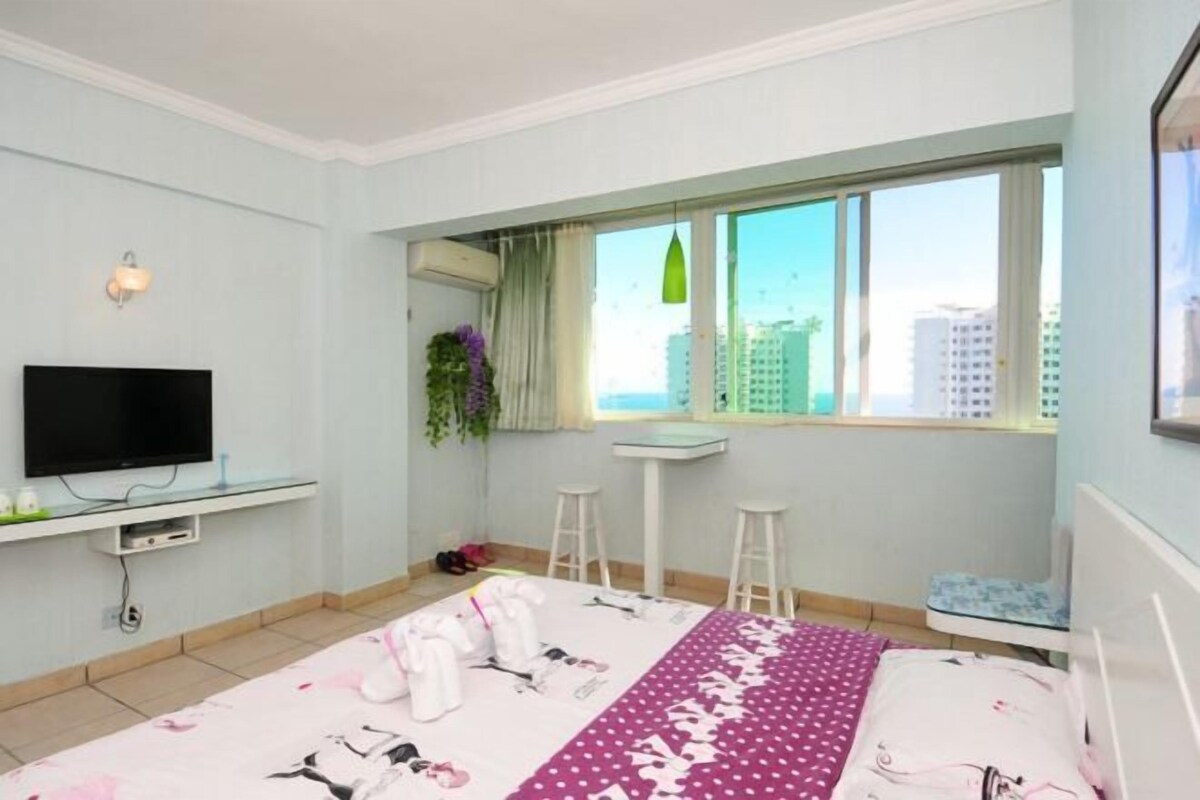 Ein Schlafzimmer mit Bett, Fernseher, Fenster mit Blick, Schreibtisch und Stuhl.