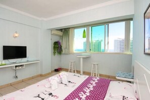 Ein Schlafzimmer mit Bett, Fernseher, Fenster mit Blick, Schreibtisch und Stuhl.