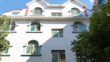 A multi-story building with a white facade, multiple windows, and balconies.