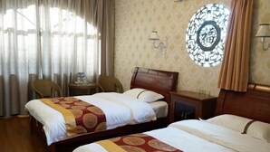 Habitación de hotel con dos camas, una mesita, una silla y un adorno en la pared.