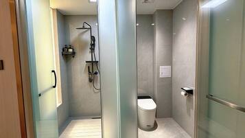 A modern bathroom with a glass partition, a shower, and a toilet.