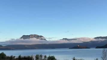 A calm lake with mountains in the background and a small island with a lighthouse.