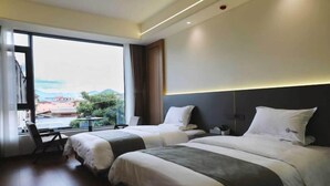 A hotel room with two beds, a large window, and a view of the cityscape. - Lugu Lake Yongzhen Hotel (Ninglang)