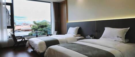 Una habitación de hotel con dos camas, un ventanal grande y vistas a la ciudad.