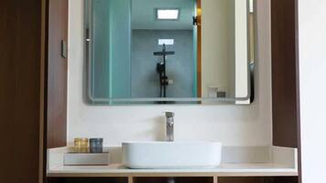 A bathroom with a white sink, a mirror, and a shower.