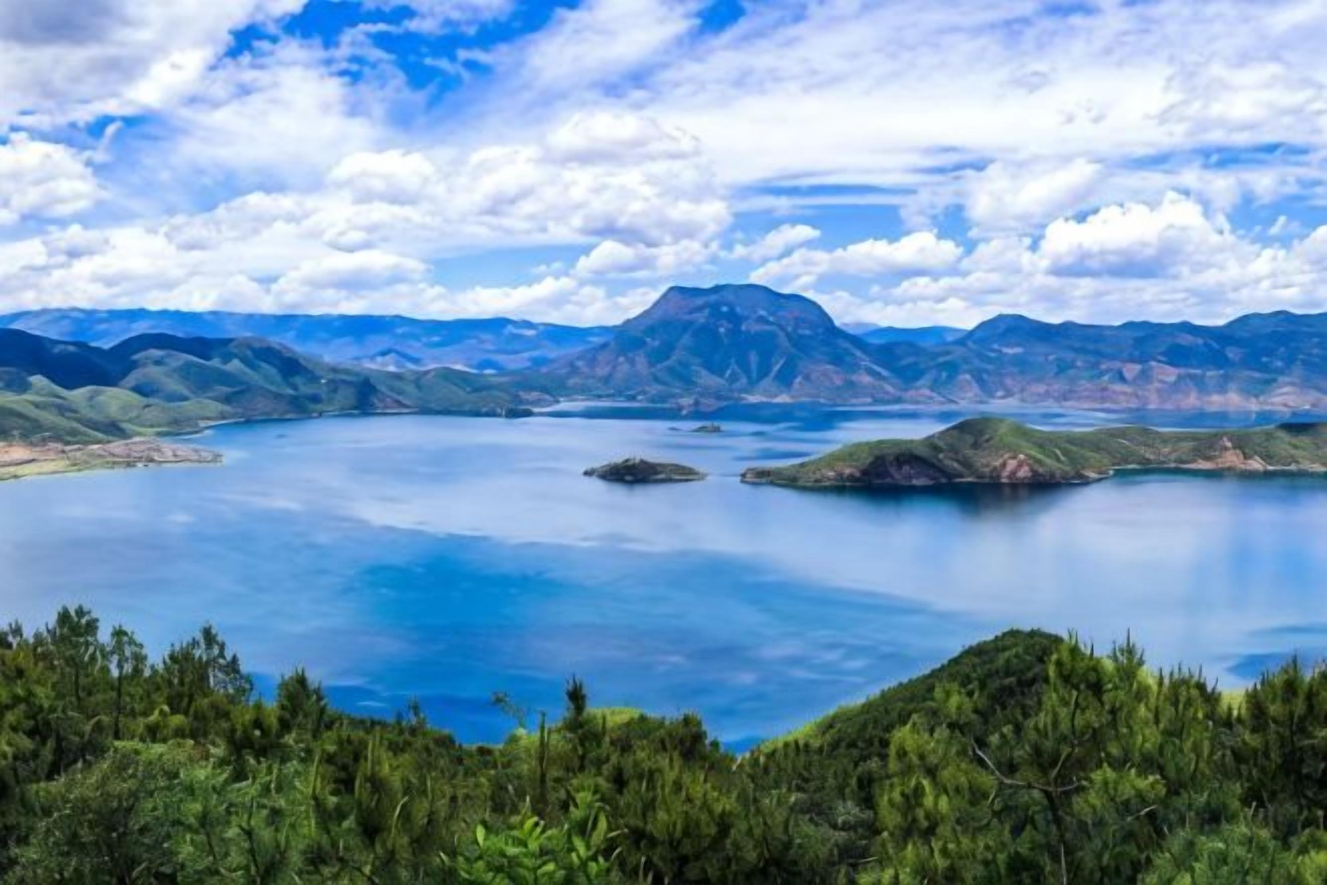 A panoramic view of a lake surrounded by mountains and dense forest.