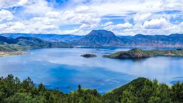 A panoramic view of a lake surrounded by mountains and dense forest.